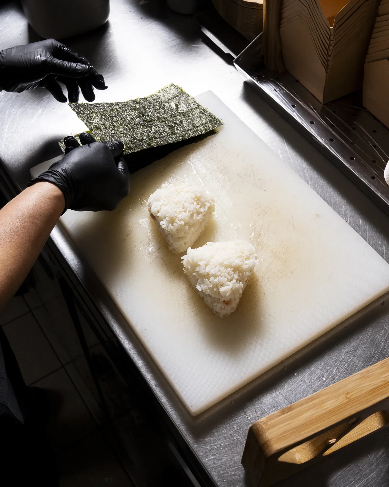 Mains gantées qui pressent un onigiri au comptoir
