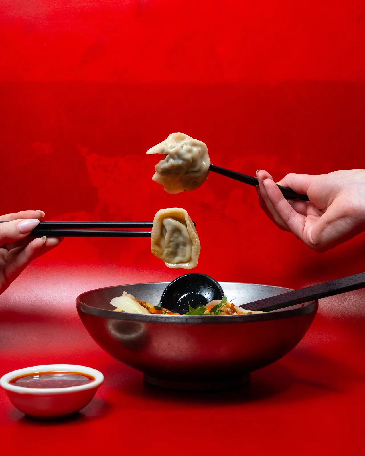 Ravioli jiaozi saisi aux baguettes au-dessus d'un bol rouge