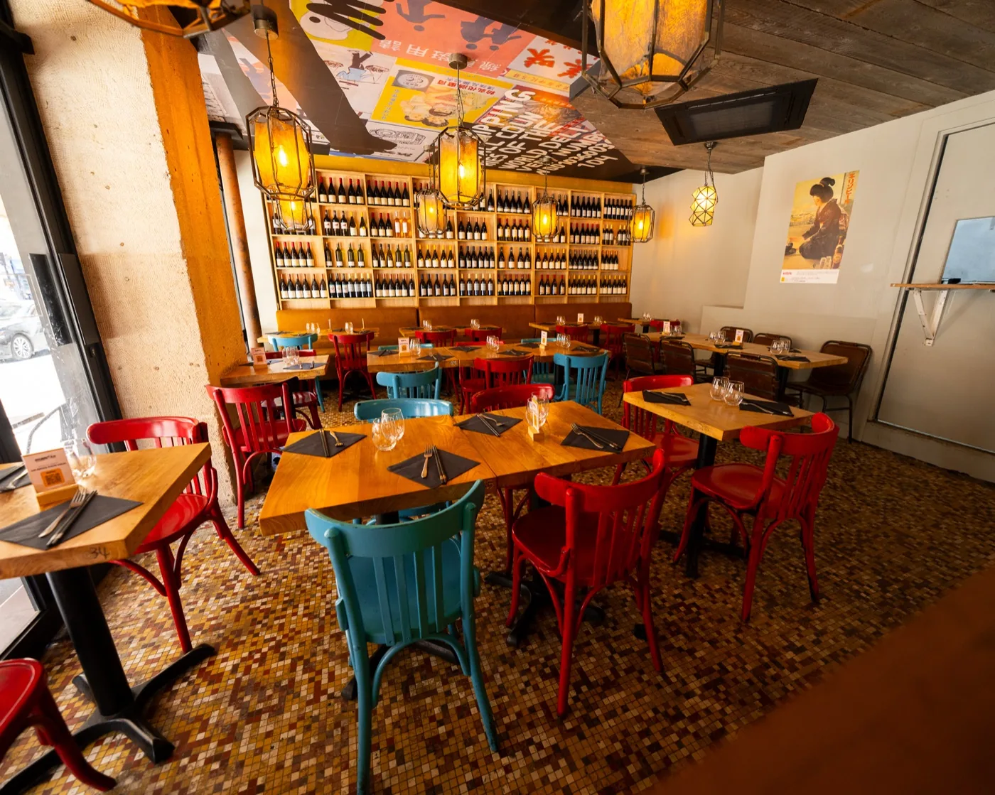 Le Peletier : salle du bistrot, chaises rouges et bleues, mur de bouteilles
