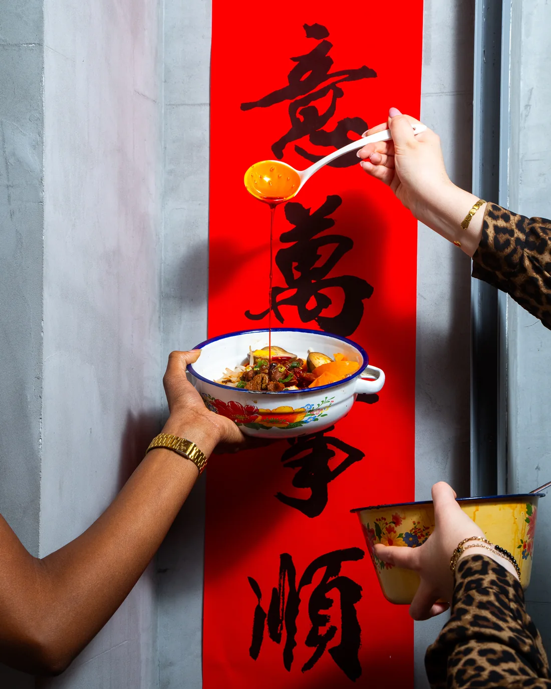 Filet d'huile pimentée versé sur une cocotte de nouilles, devant une bannière calligraphiée rouge