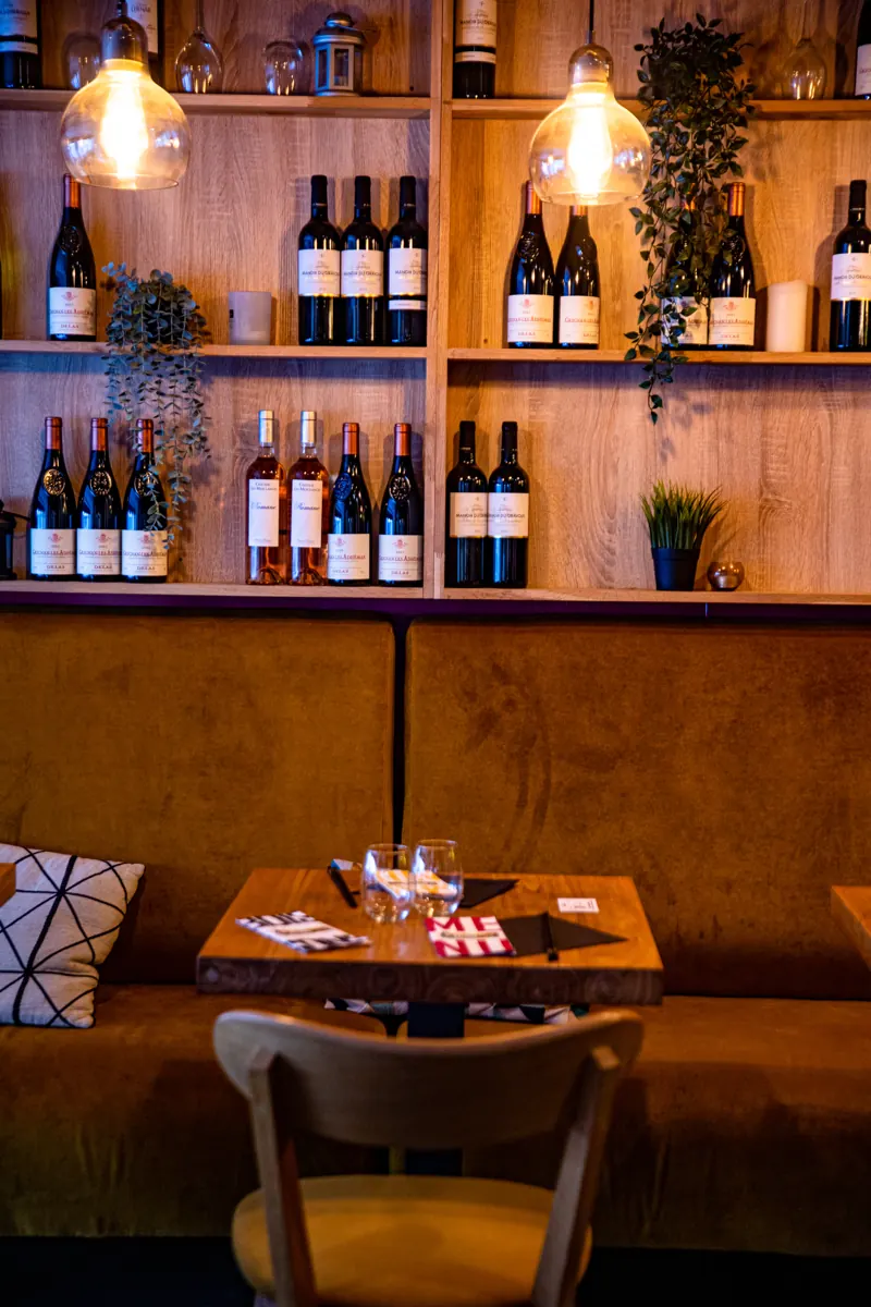 Coin banquette du Mian Fan Montparnasse devant le mur de vins, table dressée