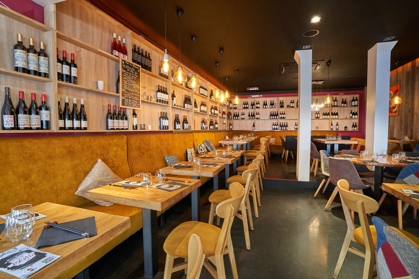 La salle du Mian Fan Montparnasse, mur de bouteilles de vin et banquettes moutarde