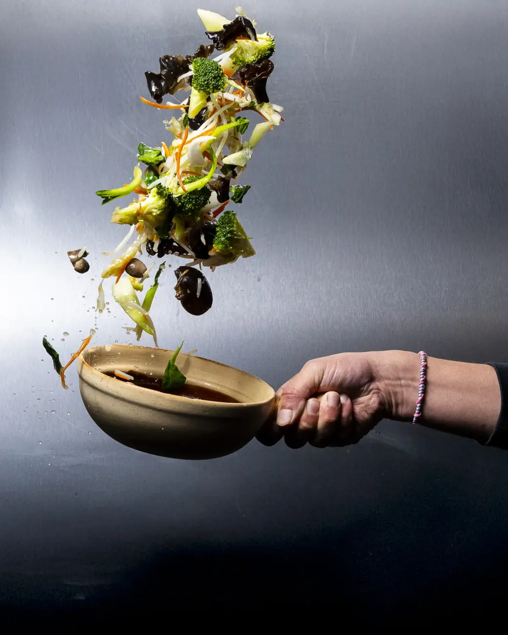 Légumes en suspension au-dessus du wok, en cuisine
