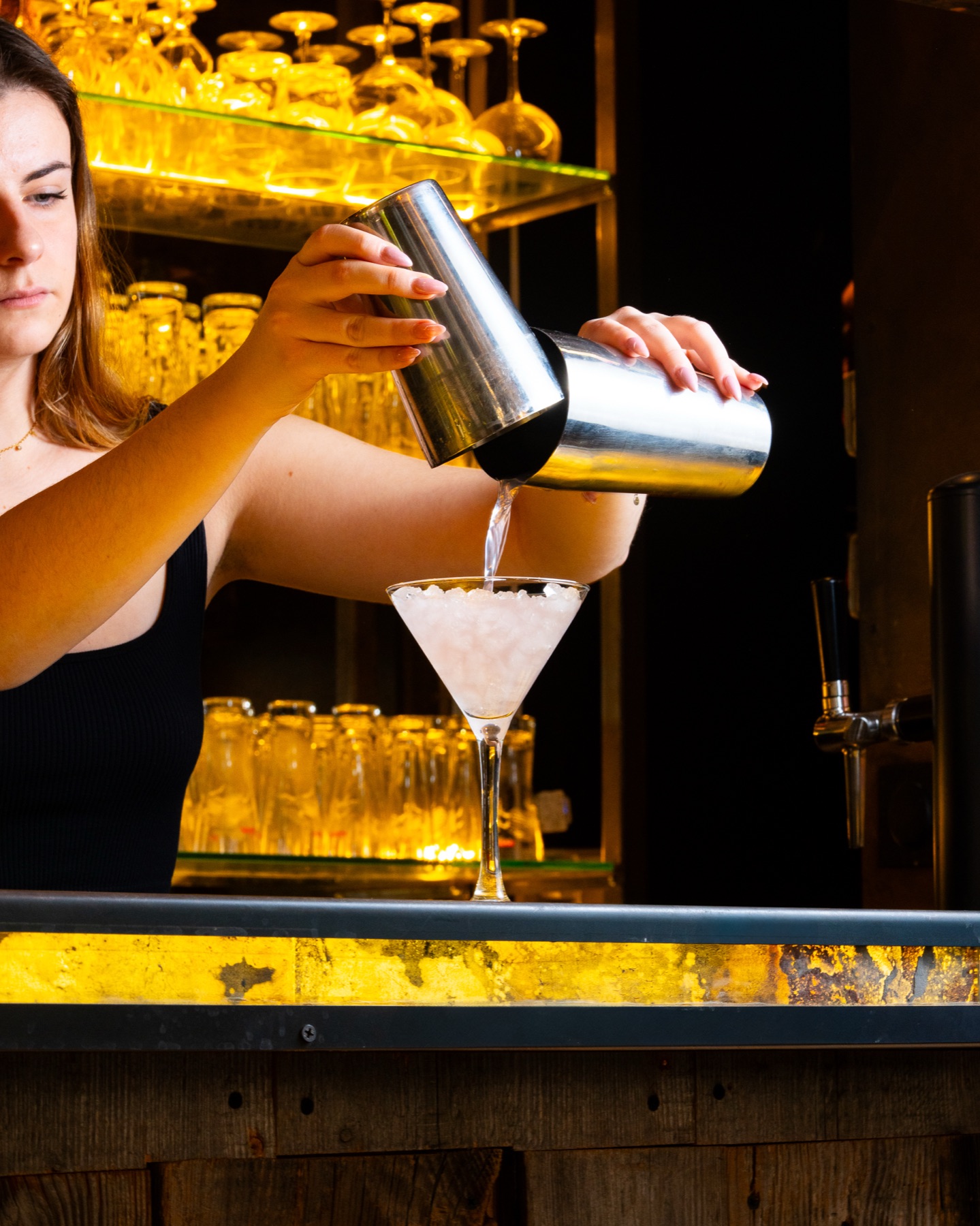 Barmaid en plein service derrière le comptoir jaune ocre du Mogador
